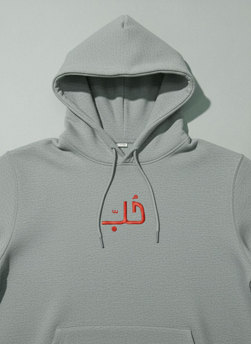 Gray hoodie with embroidered red Arabic text on a light gray background