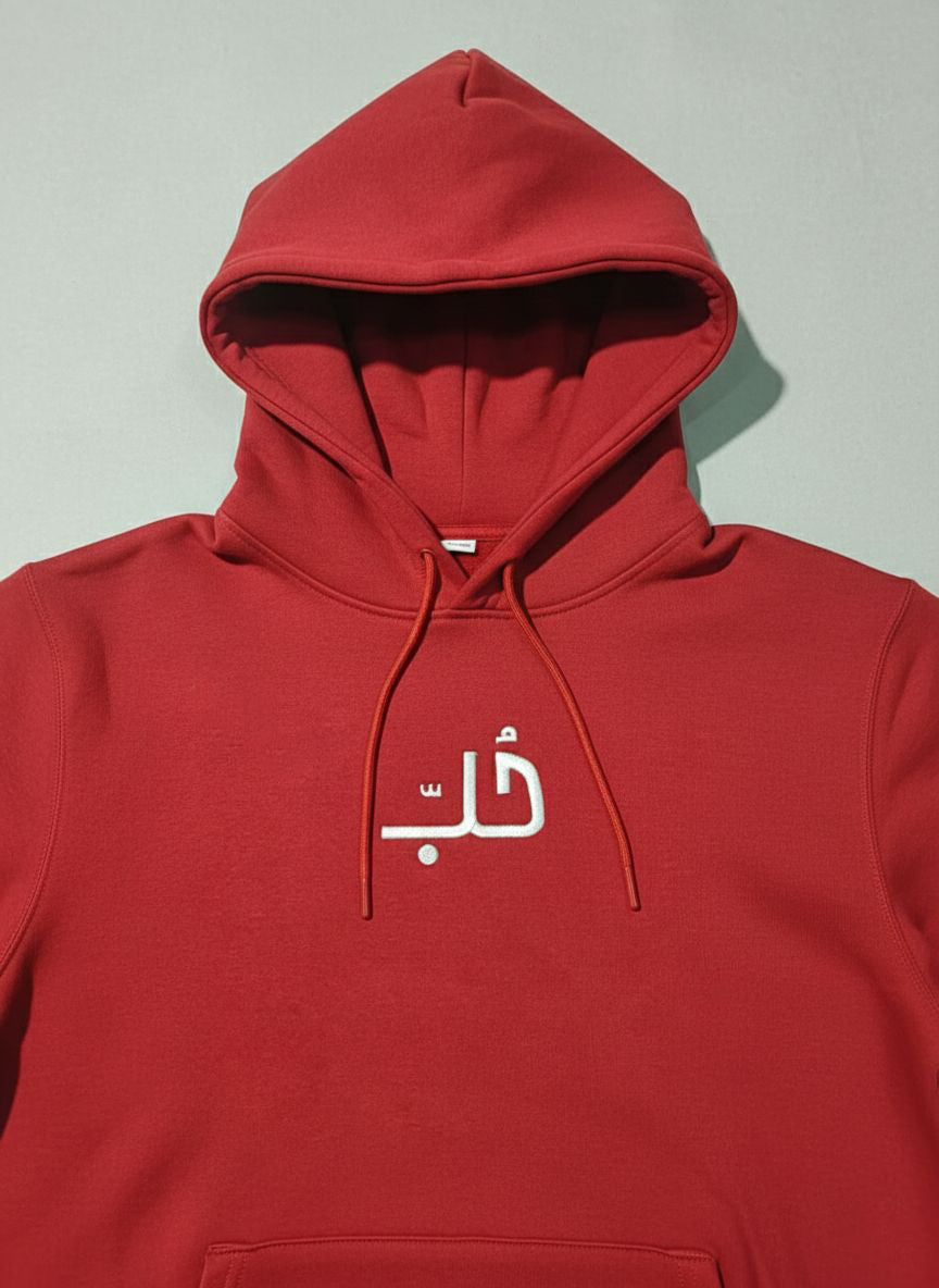 Red hoodie with  embroidered  Arabic text on a gray background