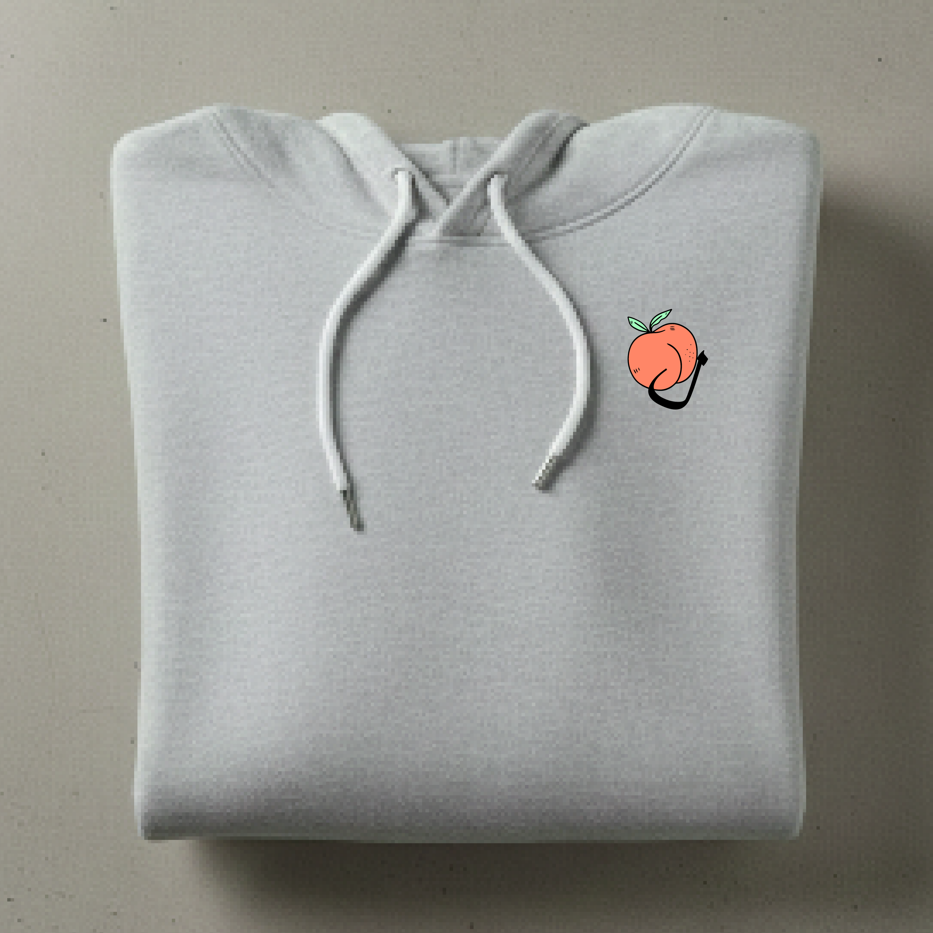 Folded gray hoodie with a small peach graphic on a beige surface