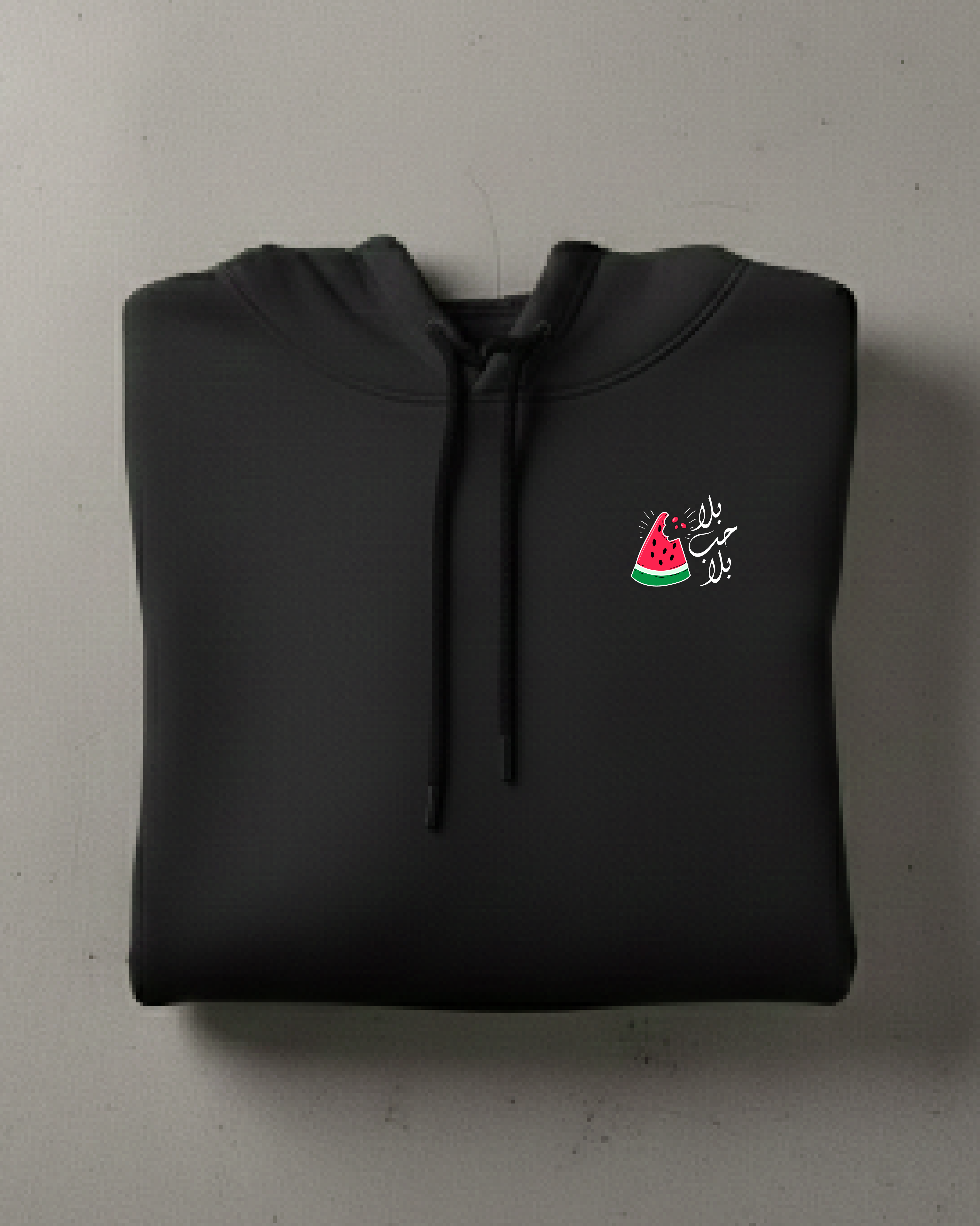 Folded black hoodie with a small colorful watermelon design on a light gray background