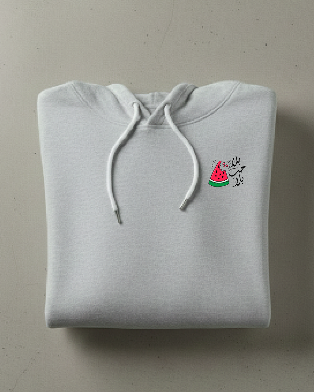 Folded gray hoodie with watermelon design and text on a beige background