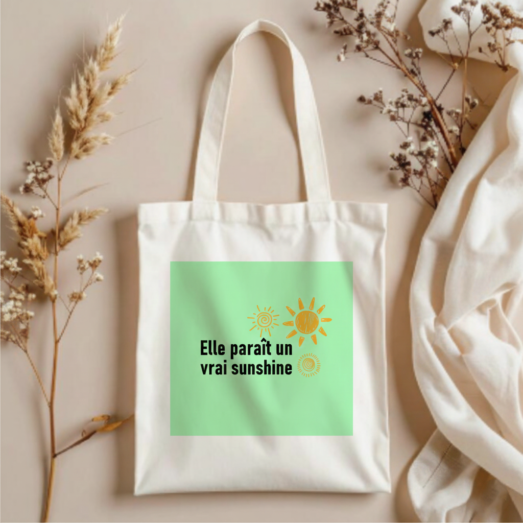 White tote bag with green label featuring sun graphics and text on a neutral background